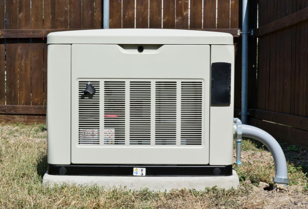 Outdoor backup generator near wooden fence